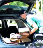 Man placing boxes in car trunk at drive thru market
