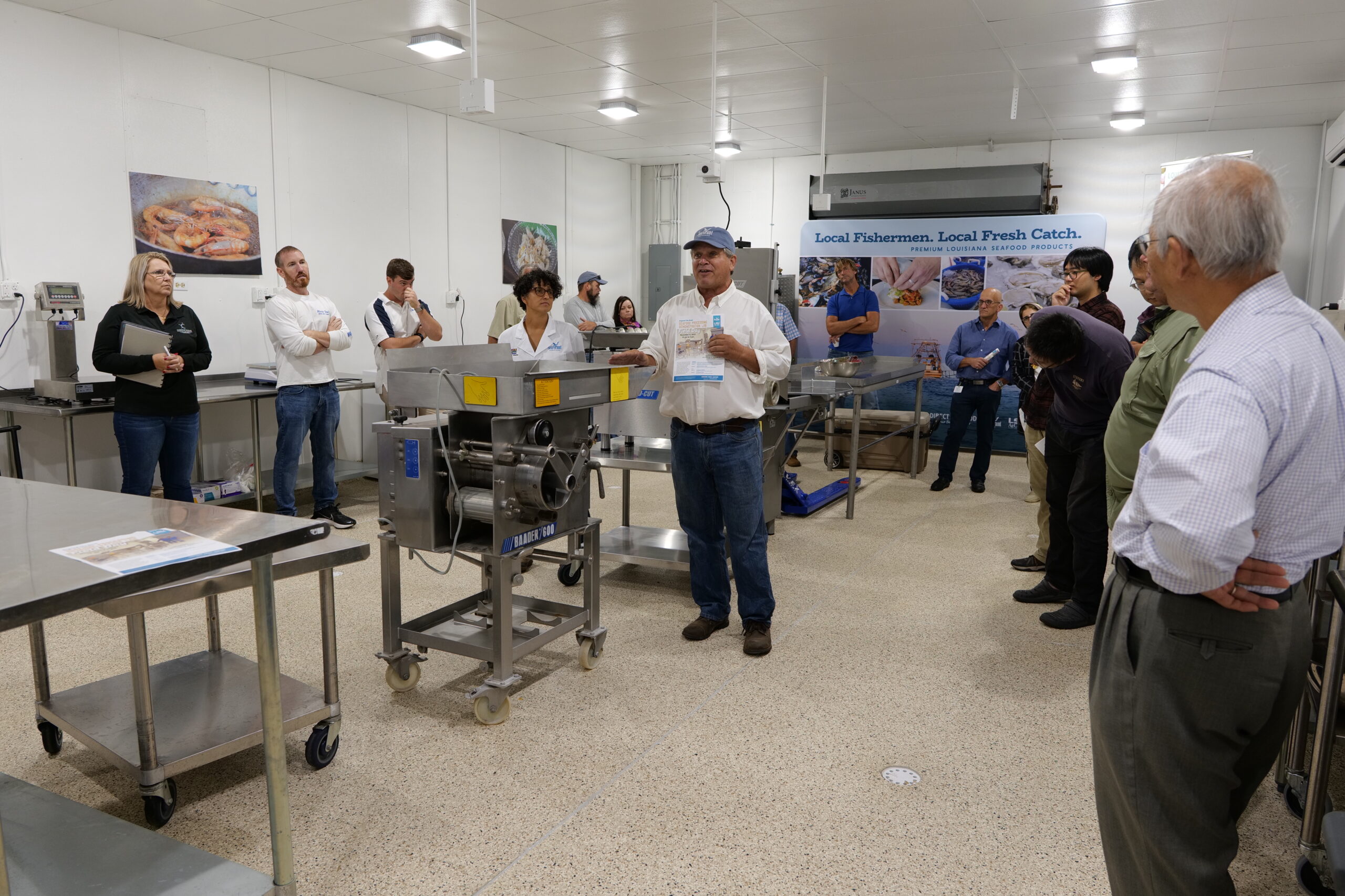 Man talking to a group of people in a food processing room.