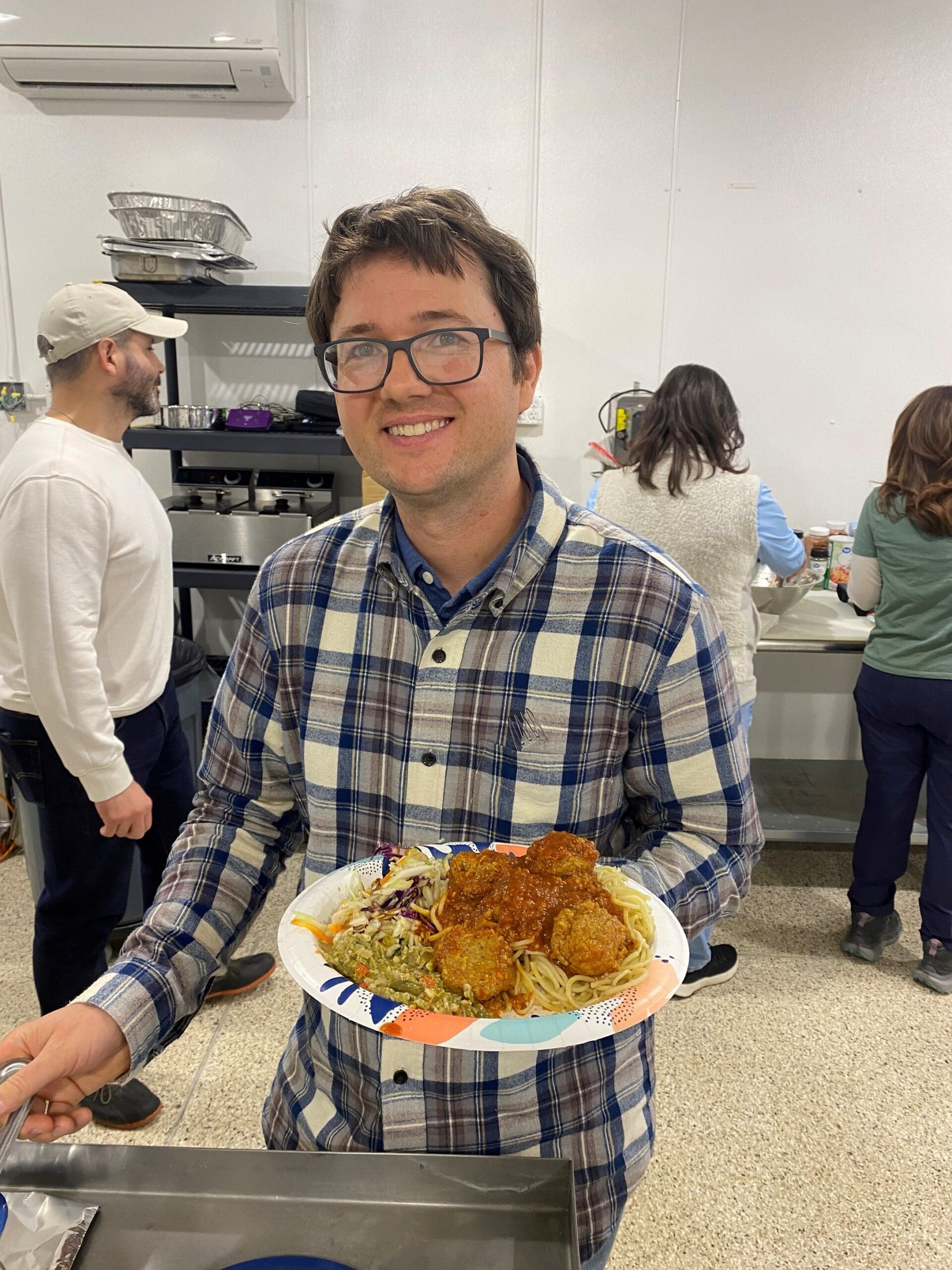 man with plate of food including spaghetti and meatballs