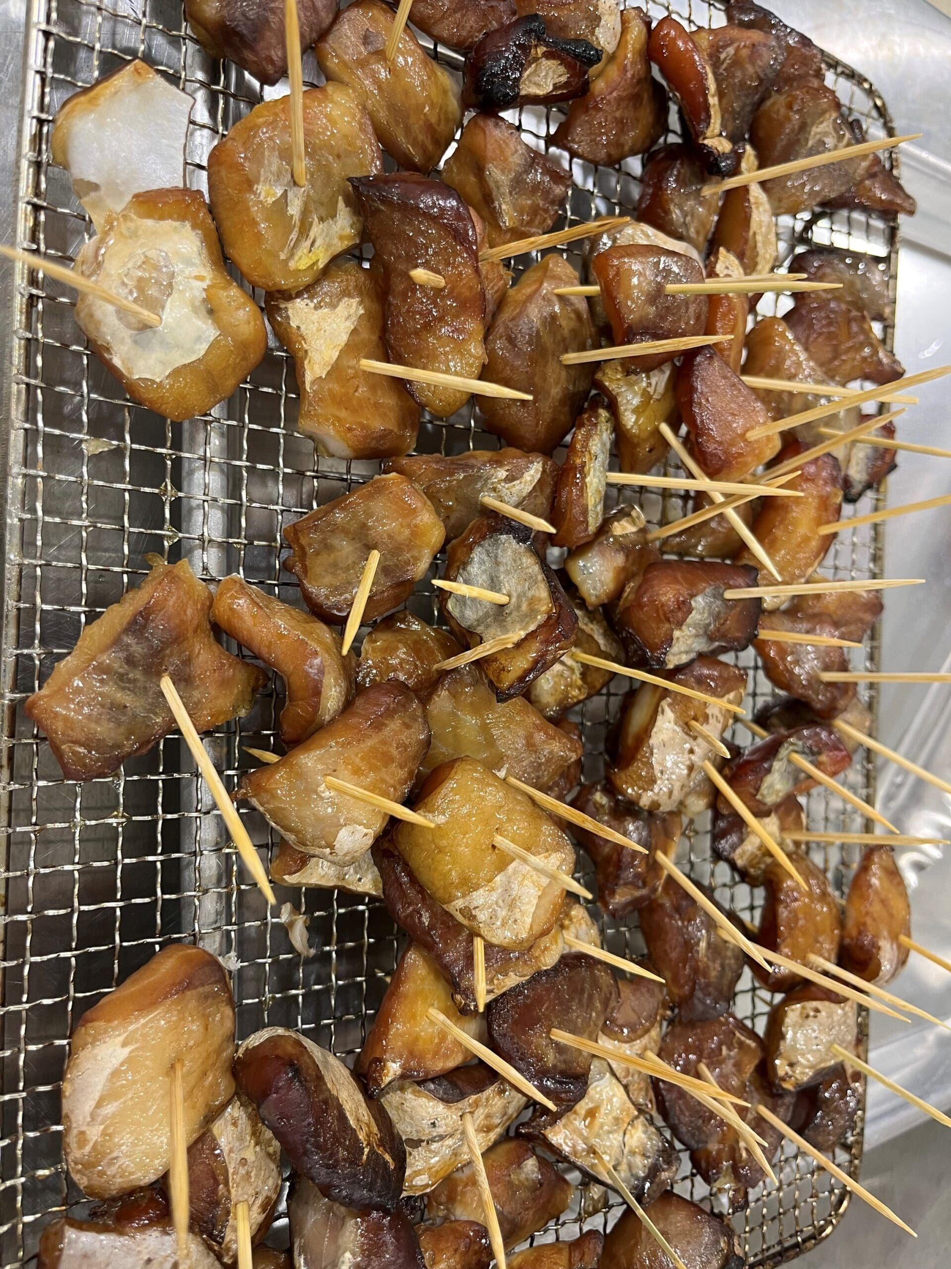 pieces of smoked fish with toothpicks on a rack