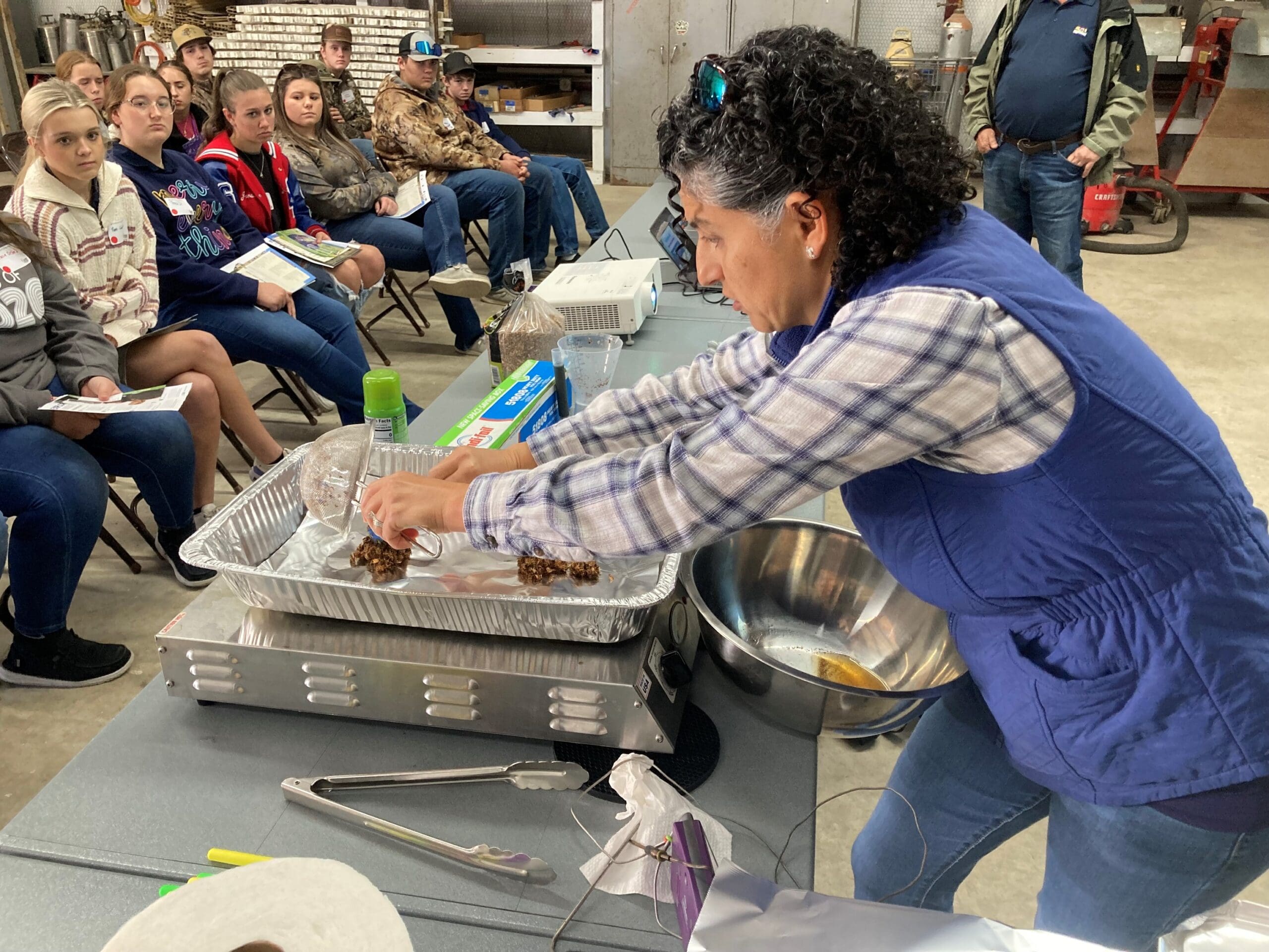 Female demonstrating smoking techniques on a cooktop to students