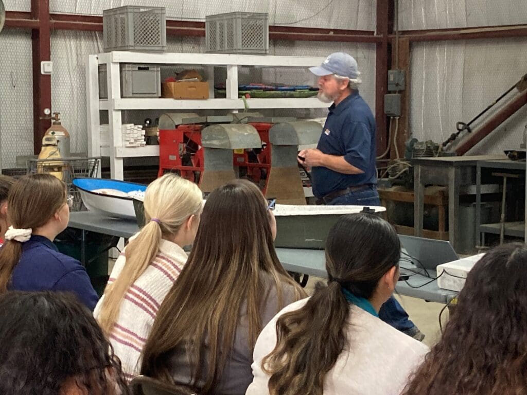 Male presenter with students in a warehouse environment